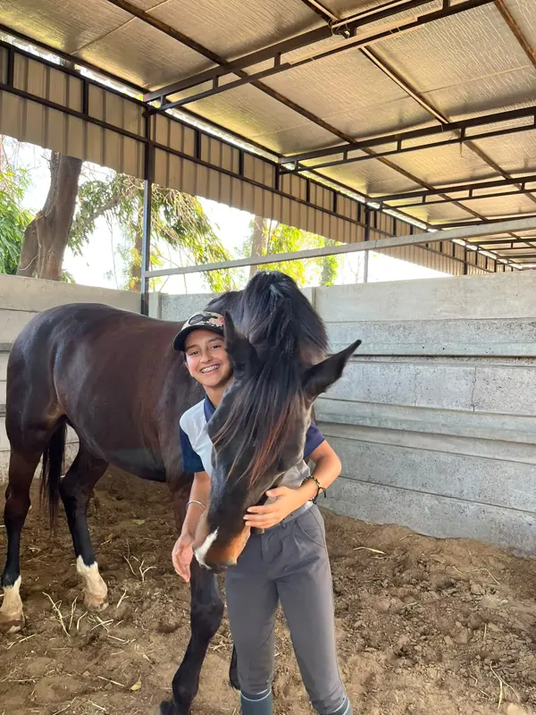 Amara smiling and hugging her horse in the stable
