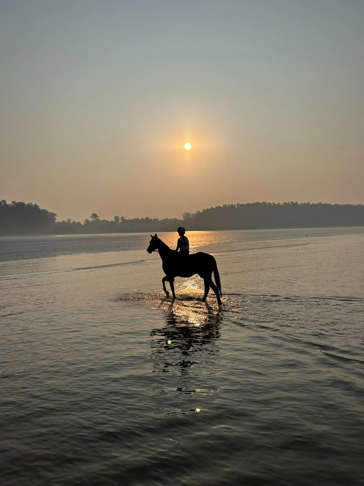 Amara riding through shallow water at sunrise